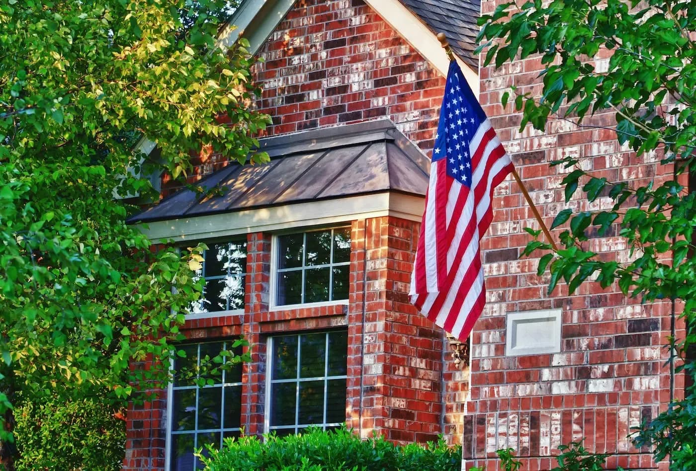 American flag displayed on brick residential home with ivy-covered walls