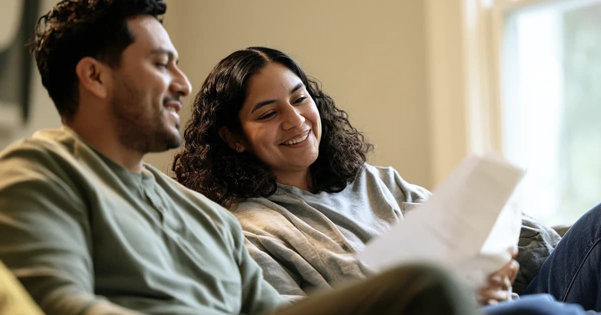 Smiling couple sitting together reviewing documents in a bright indoor setting