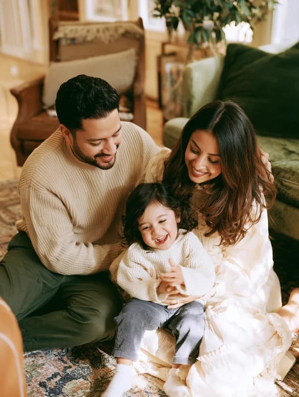Happy family of three smiling together in a warm, welcoming home setting