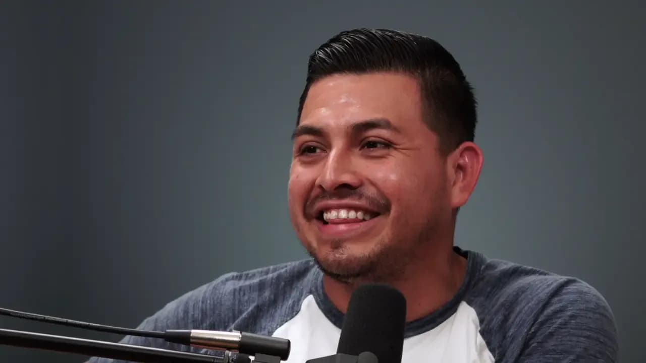 Man smiling while speaking into a microphone in a podcast studio