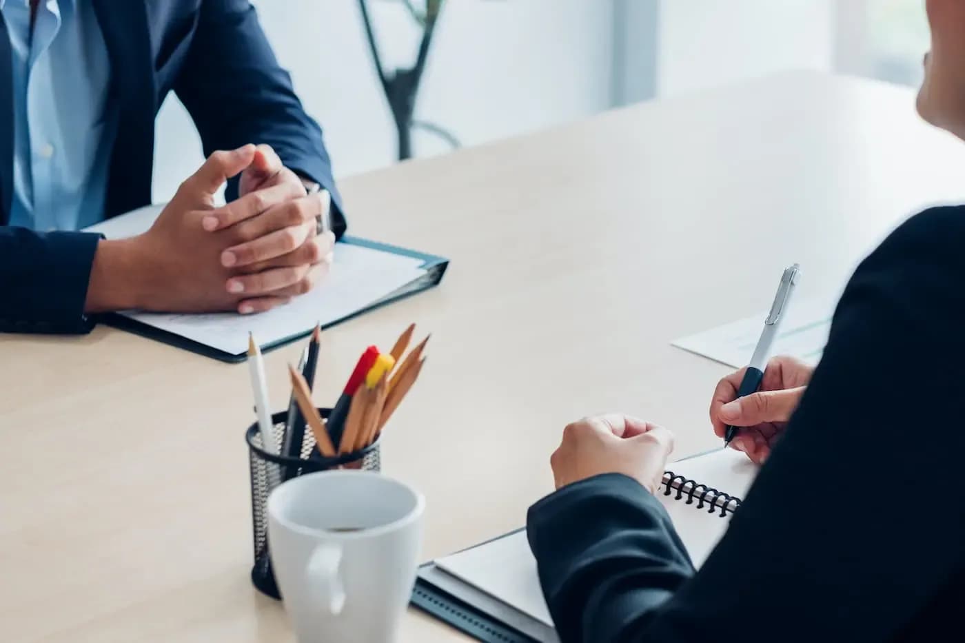 Two professionals at a desk during a consultation, one taking notes